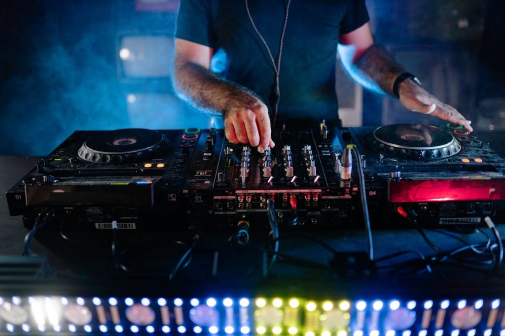 DJ performing with mixing equipment at a nightclub, vibrant nightlife scene.